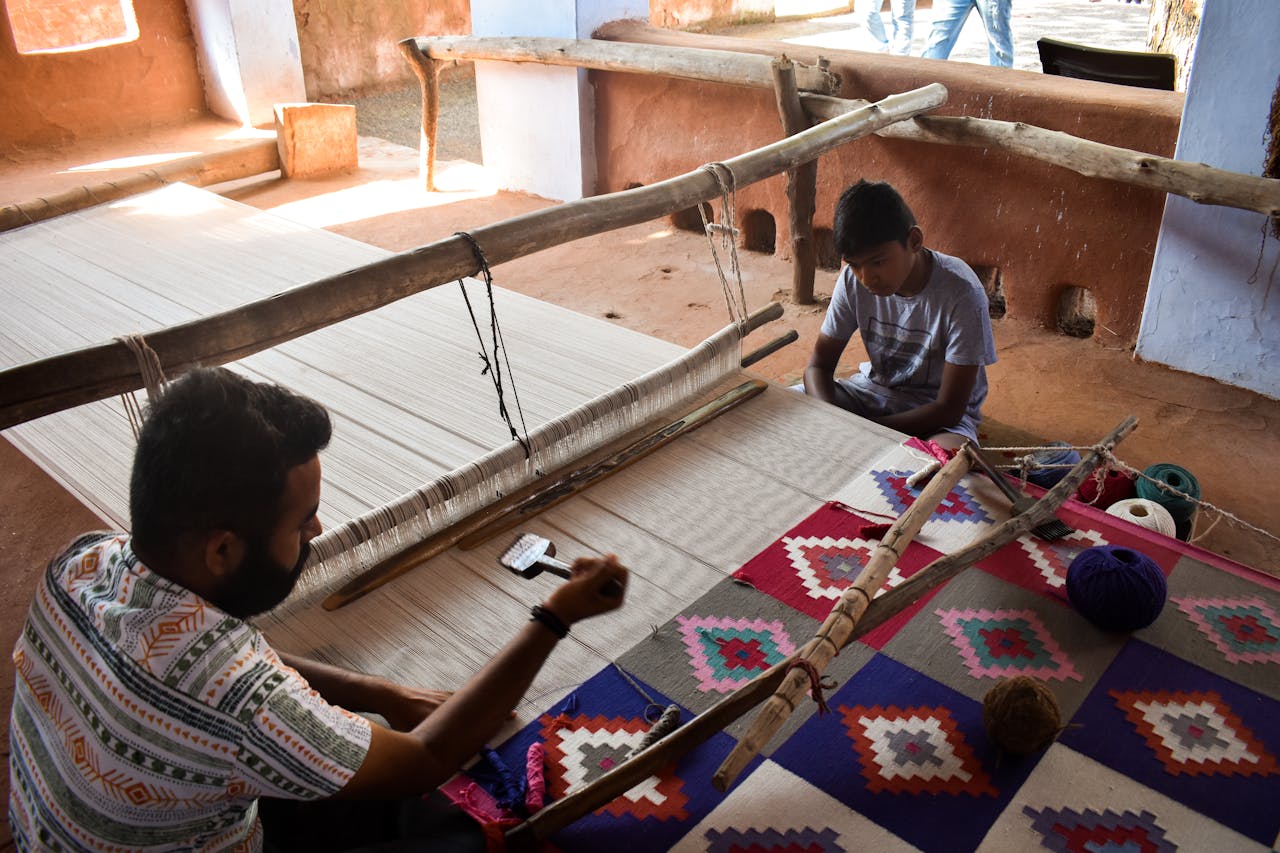 Artisan and child weaving a colorful carpet on a handloom in Jodhpur, Rajasthan.